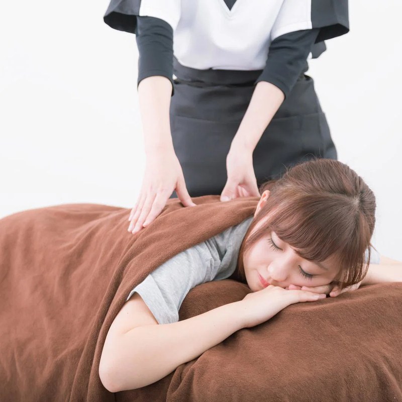 うつ伏せのお客様に施術を行うセラピスト